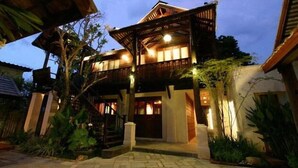 A two-story wooden house with a balcony, surrounded by tropical vegetation. - Bann Tazala Exclusive Residence (Chiang Mai)