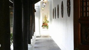 A corridor with white walls, wooden columns, and a hanging light fixture. - Bann Tazala Exclusive Residence (Chiang Mai)
