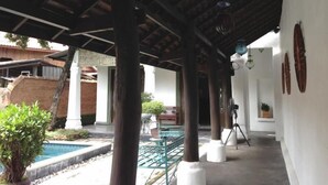 A covered outdoor area with a pool, columns, and potted plants. - Bann Tazala Exclusive Residence (Chiang Mai)