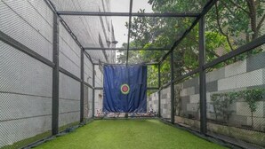 A batting cage with artificial turf and a blue netting backdrop. - 39 Boulevard Executive Residence (Bangkok)