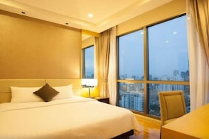 A hotel room with a large bed, a chair, a nightstand, and a window with a city view. - 39 Boulevard Executive Residence (Bangkok)