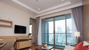 A modern hotel room with a large window, a flat-screen TV, a desk, and a comfortable seating area. - 39 Boulevard Executive Residence (Bangkok)