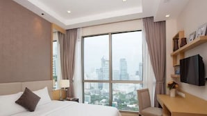 A hotel room with a large bed, a desk, a chair, and a TV. - 39 Boulevard Executive Residence (Bangkok)
