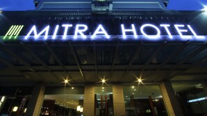 The exterior of the Mitra Hotel with illuminated signage.