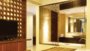 A modern bathroom with a large mirror, a sink, and a television mounted on a wooden panel.