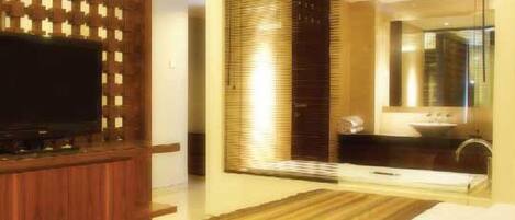 A modern bathroom with a large mirror, a sink, and a television mounted on a wooden panel.