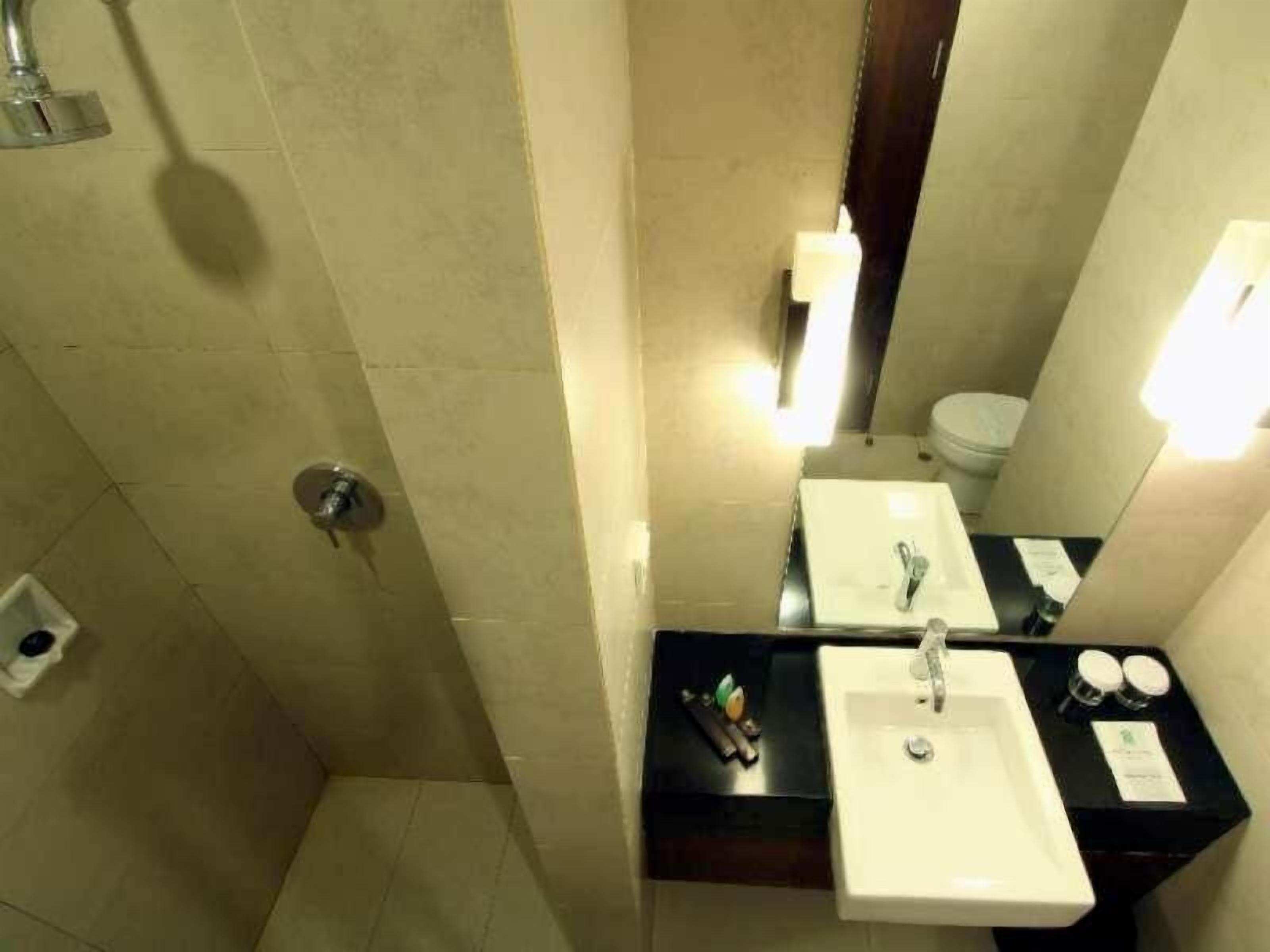 Et badeværelse med bruser, to håndvaske, et spejl og et toilet.