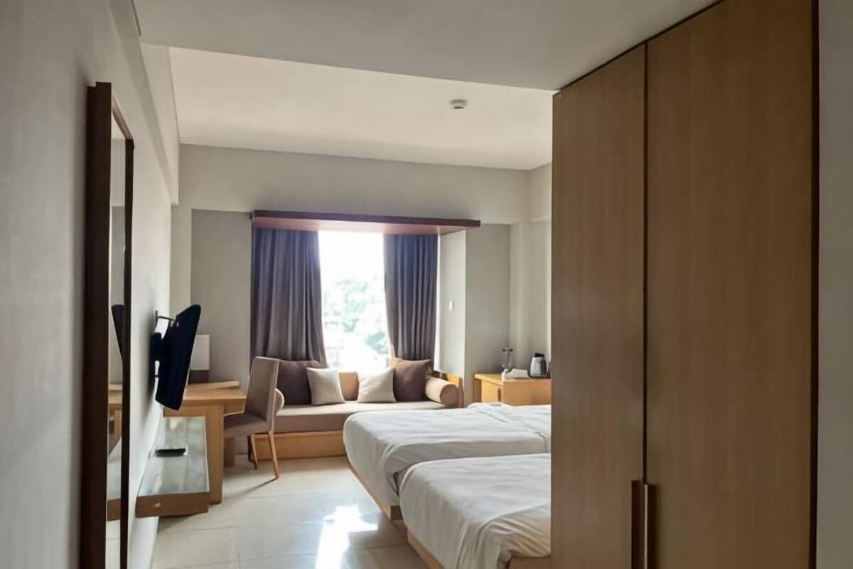 A hotel room with a bed, bedside table, chair, and a large wardrobe.