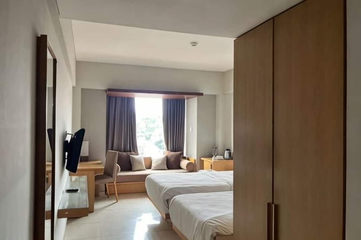 A hotel room with a bed, bedside table, chair, and a large wardrobe.