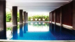 A swimming pool with clear blue water, surrounded by columns and a view of greenery. - Mitra Hotel Bandung (Bandung)