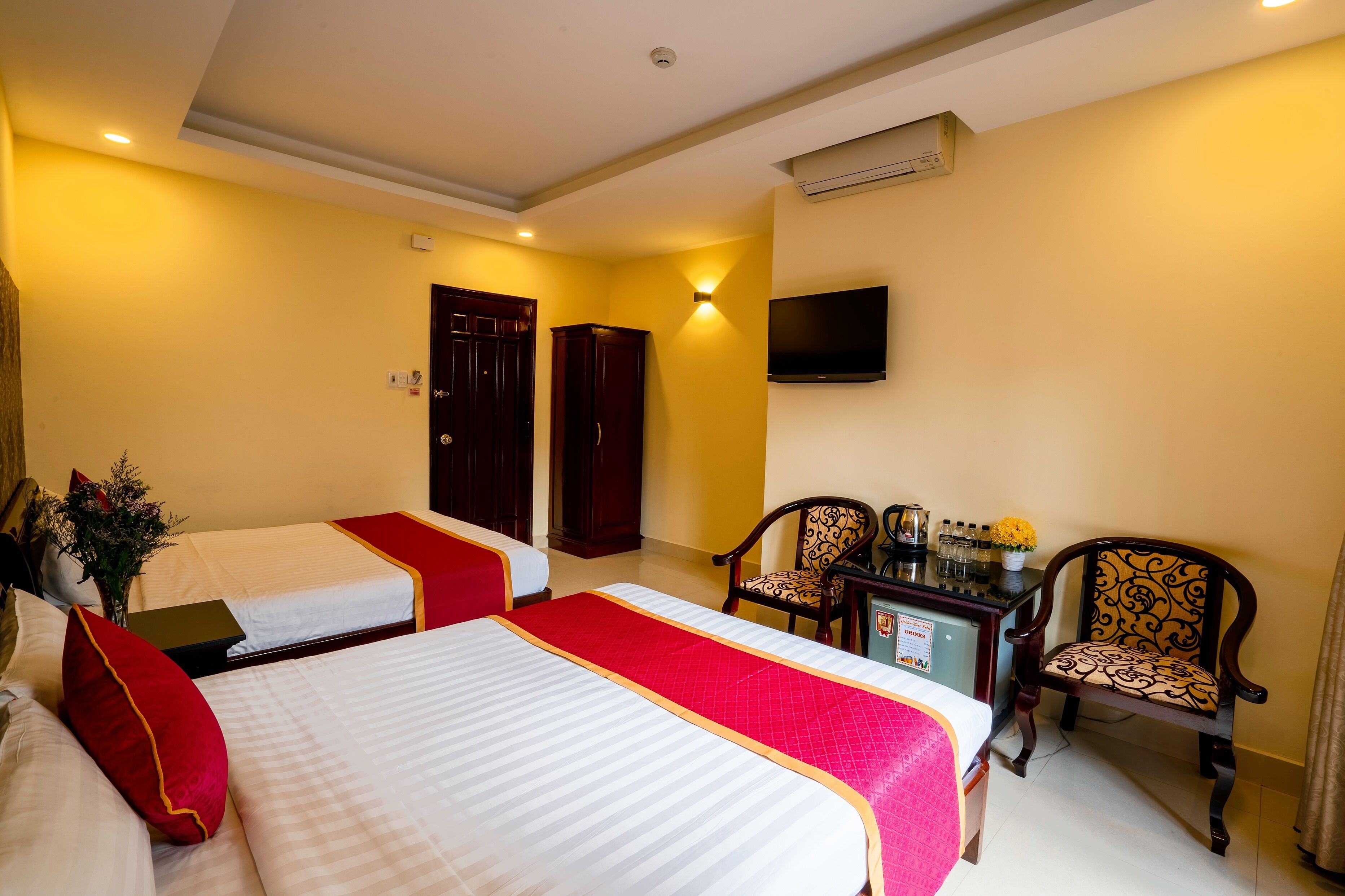 Une chambre d’hôtel avec deux lits, un bureau, une chaise et un téléviseur fixé au mur.