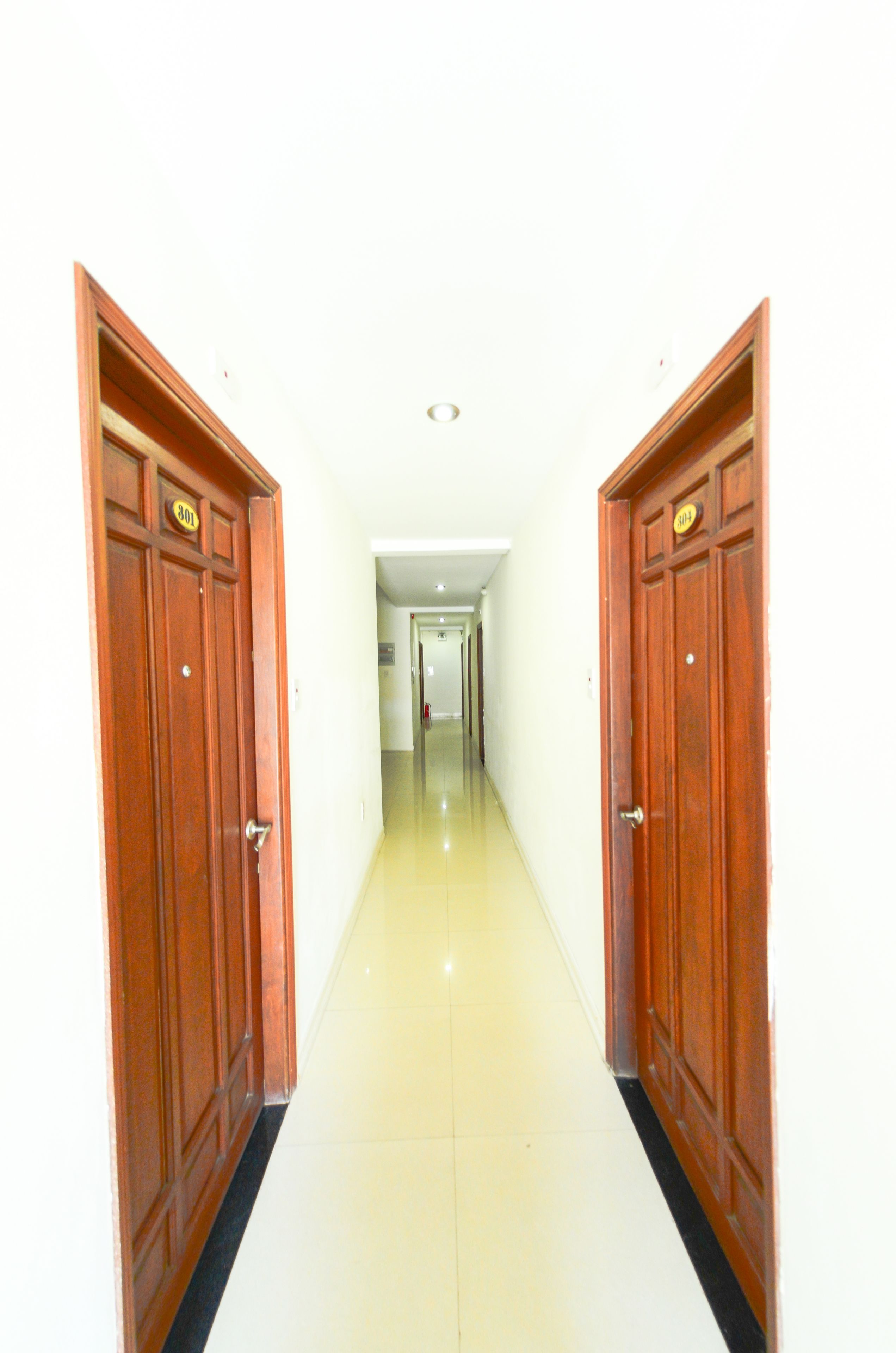 A hallway with wooden doors, a tiled floor, and a light-colored wall.