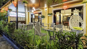 An outdoor dining area with wicker furniture and string lights. - Golden River Hotel (Da Nang)
