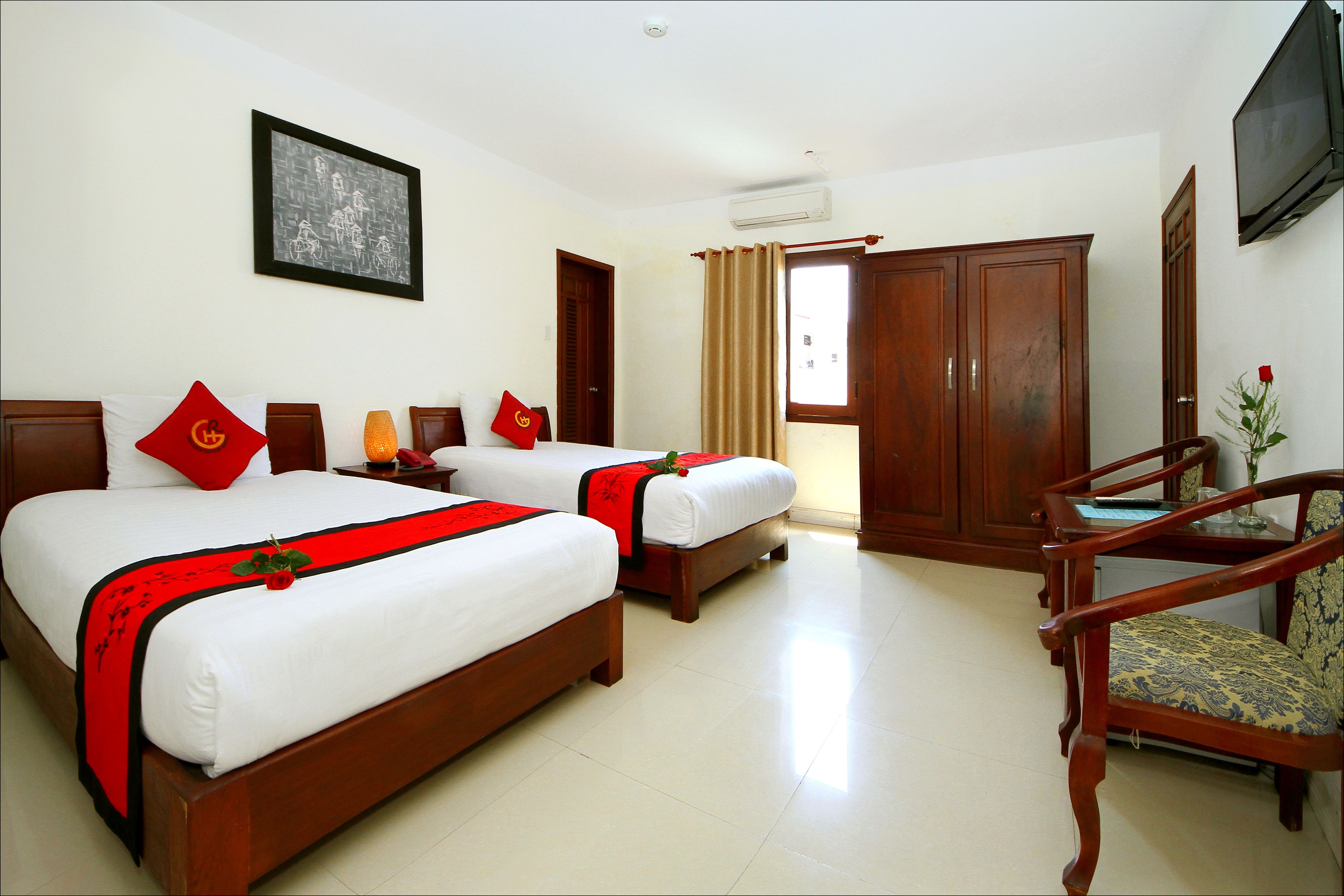 A hotel room with two beds, a wooden wardrobe, a television, and a chair.