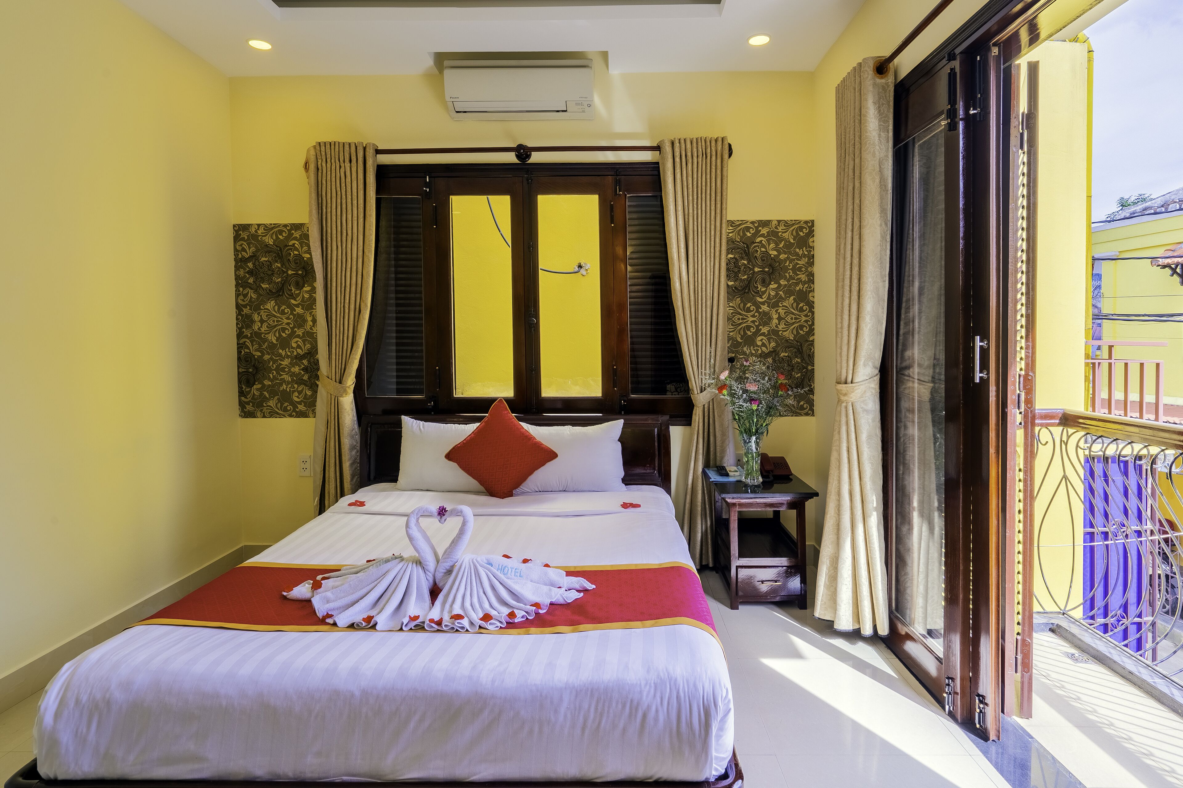 A hotel room with a bed, curtains, a window, and a balcony.