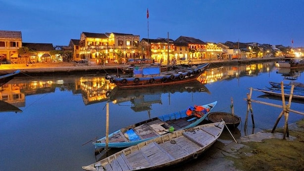 A waterfront area with traditional buildings, boats docked, and calm water reflecting the structures. - Golden River Hotel (Da Nang)