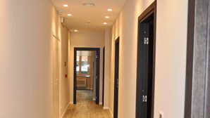 A hallway with wooden flooring, white walls, and recessed lighting. - Dea Roma Inn (Rome)
