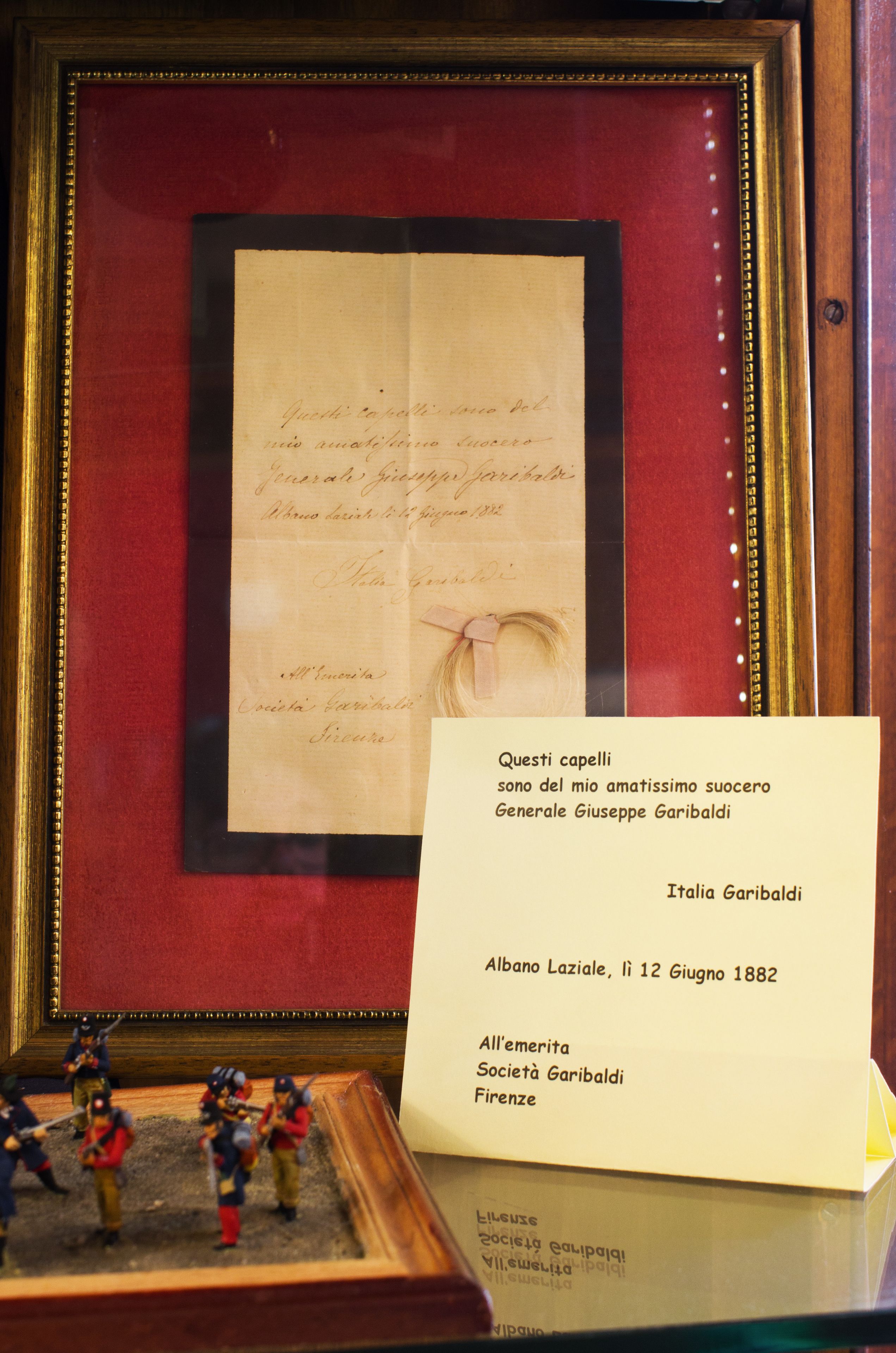 A framed historical document with a handwritten note and a small figurine of soldiers.
