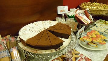 A buffet table with a variety of food items including a large pie, cheeses, and packaged snacks.