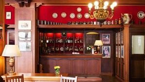 A bar area with wooden paneling, a chandelier, and a variety of bottles and glasses. - Hotel Città Dei Mille (Bergamo)