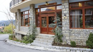 Un edificio de piedra con entrada de madera, un balcón y un cartel que dice 'Hotel'.