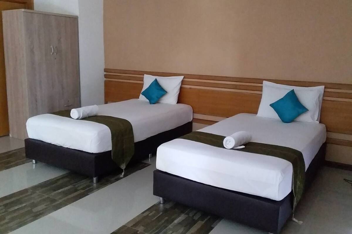 Ein Hotelzimmer mit zwei Betten, einem Kleiderschrank und einem gefliesten Boden.