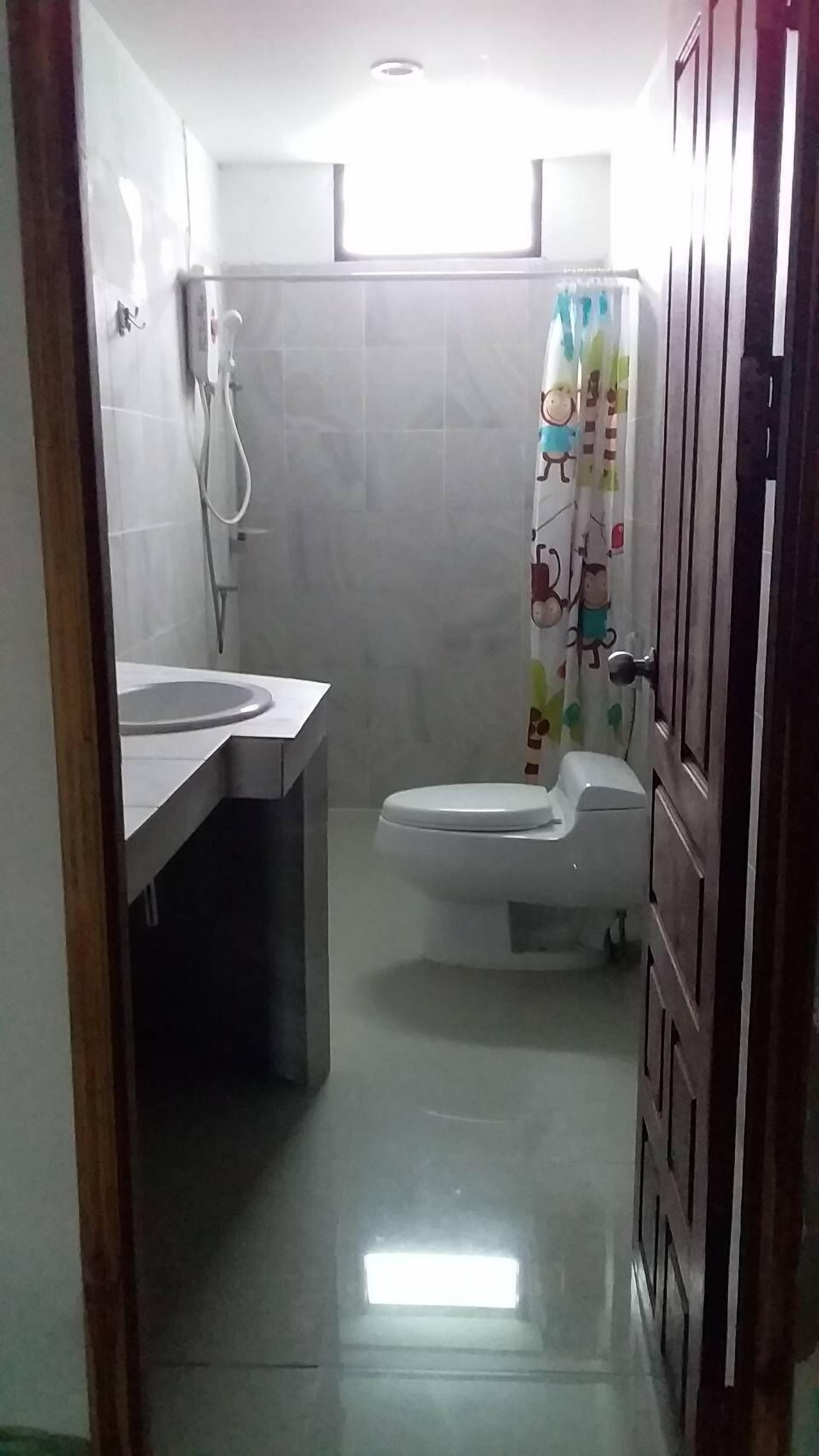 A small bathroom with a toilet, sink, and shower.