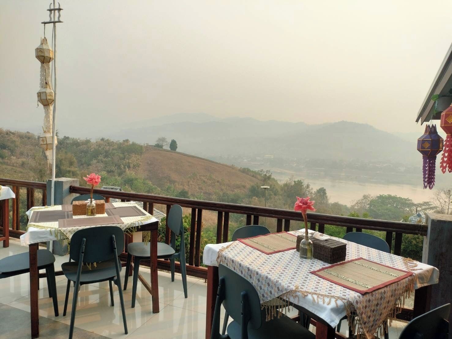 Una terraza con mesas y sillas, con vistas a un valle con un río y colinas.