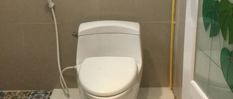 Un baño con inodoro, ducha y puerta de vidrio con diseño floral.