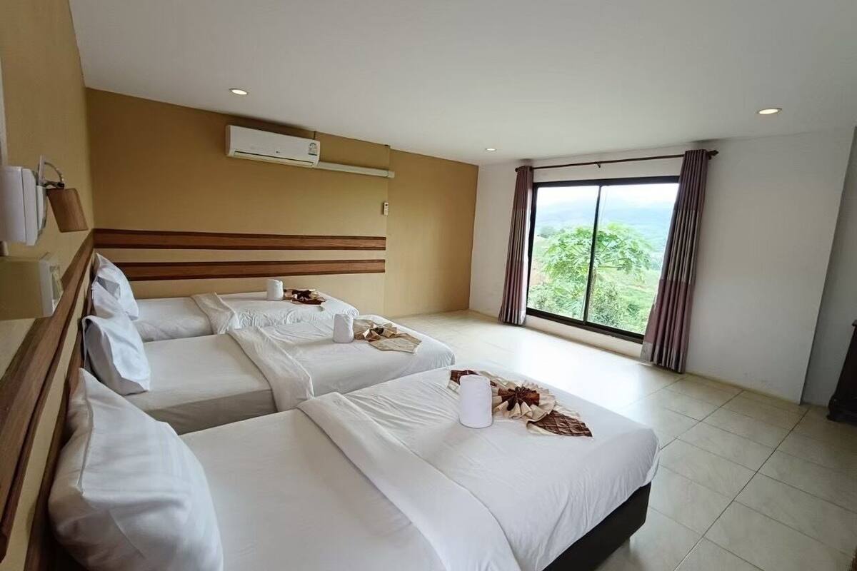 Ein Hotelzimmer mit zwei Betten, einem großen Fenster mit Blick und einer Klimaanlage an der Wand.