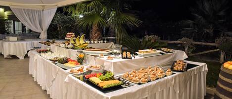 A buffet table with various food items under a tent.