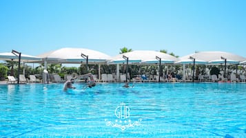 Una piscina al aire libre, sombrillas, sillones reclinables de piscina