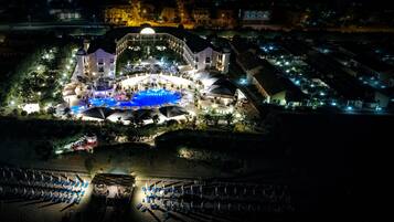 Un grande resort con piscina centrale, diverse aree ristorazione e varie disposizioni di posti a sedere all'aperto.