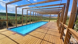 A wooden deck with a pool, surrounded by a wooden pergola, overlooking a vineyard. - Endless Vineyards at Wildekrans Wine Estate (Bot River)