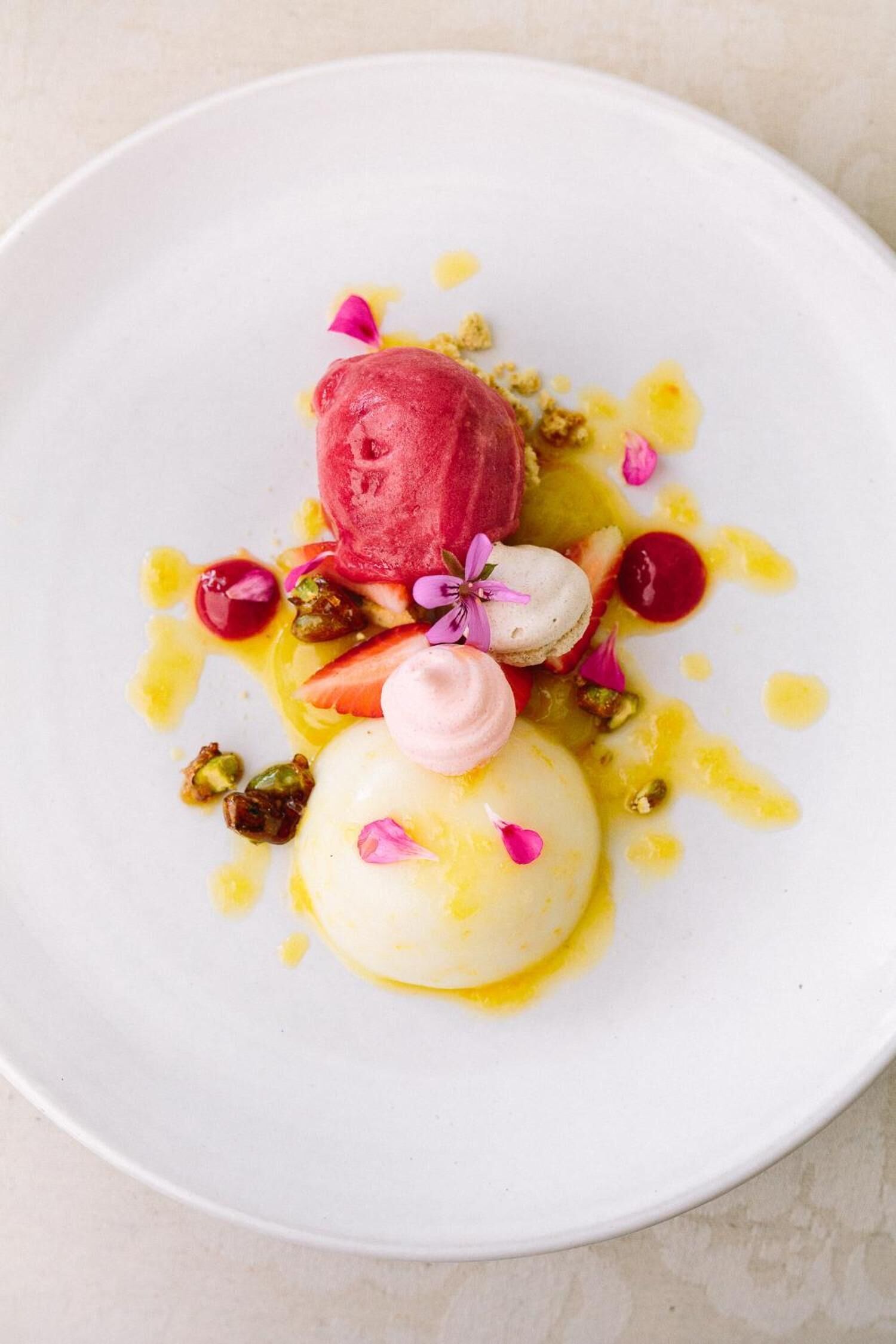 Un plato con postre, una bola de helado, un macaron y algunas nueces.