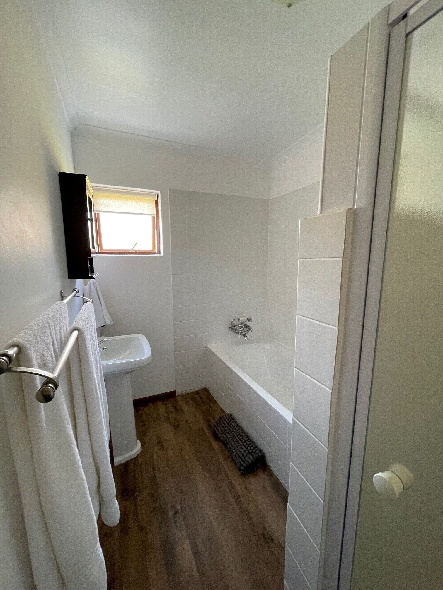 Een badkamer met een witte wastafel, een bad en een raam.