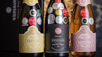 Three bottles of wine with labels and awards, placed on a reflective surface.