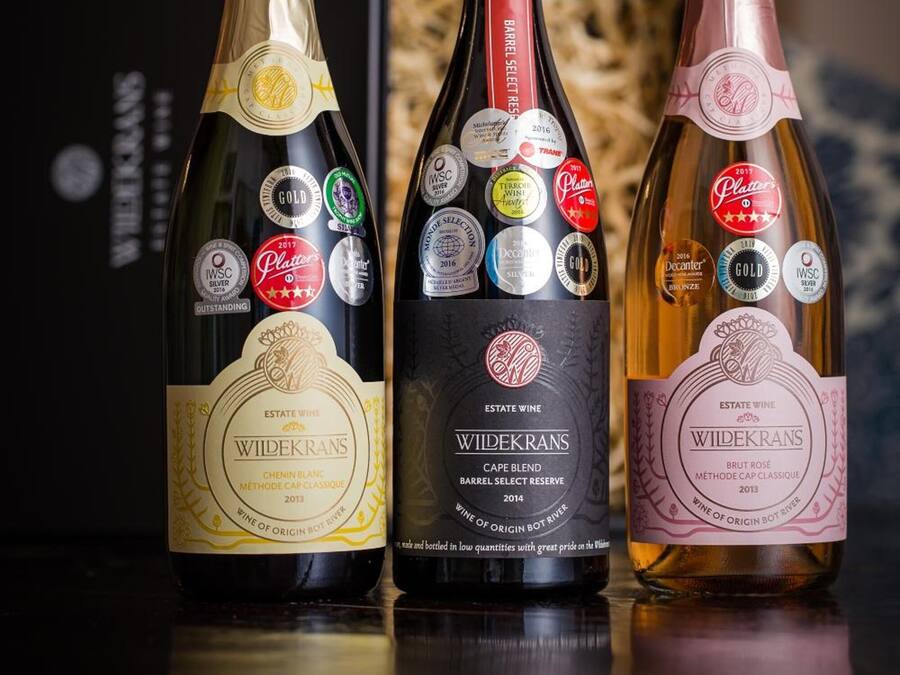 Three bottles of wine with labels and awards, placed on a reflective surface.