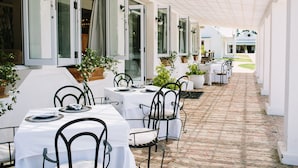 An outdoor dining area with tables and chairs, potted plants, and a brick pathway. - Endless Vineyards at Wildekrans Wine Estate (Bot River)