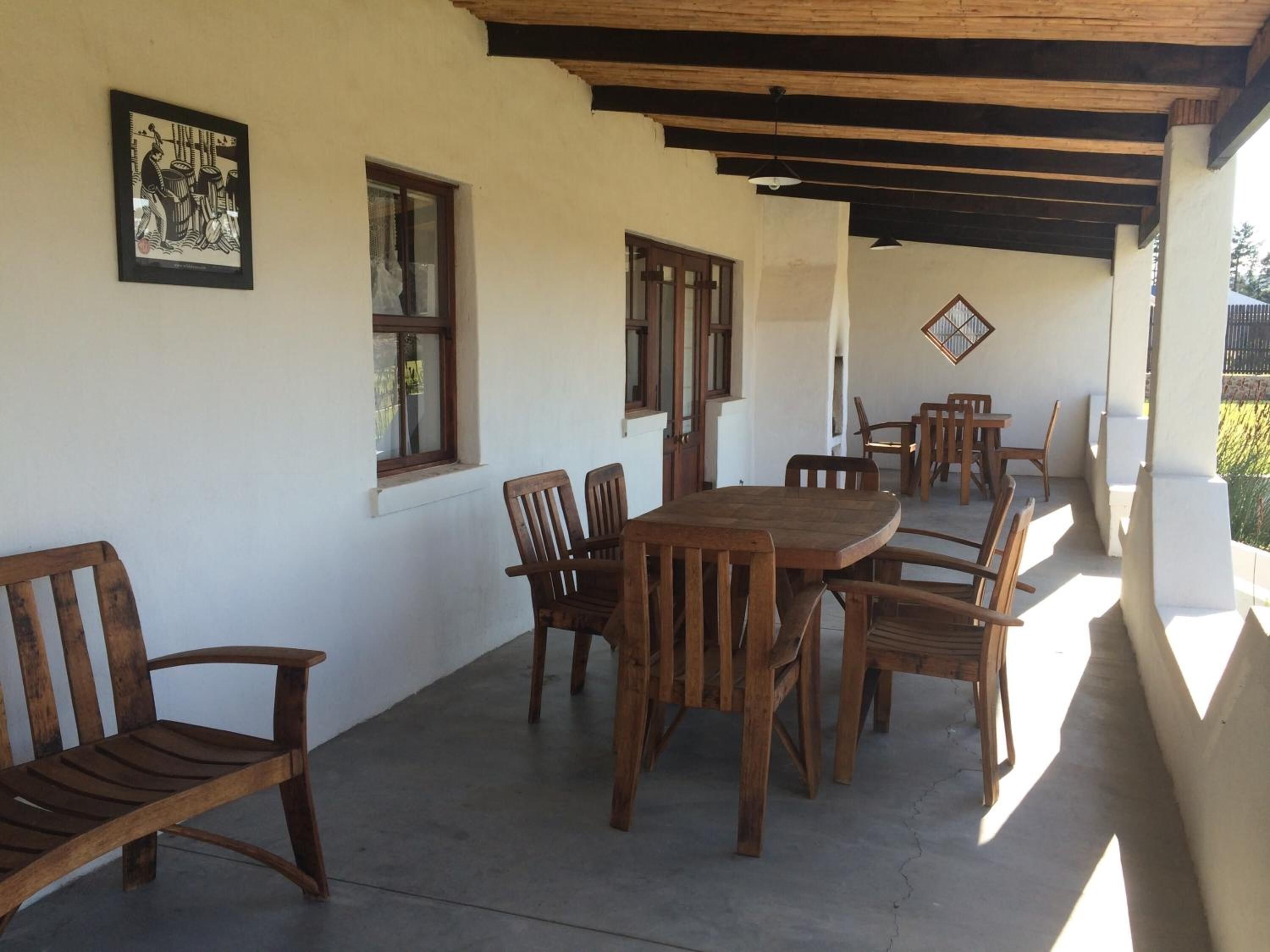 Un patio techado con mesa y sillas de madera, una obra de arte en la pared y una ventana con vistas.