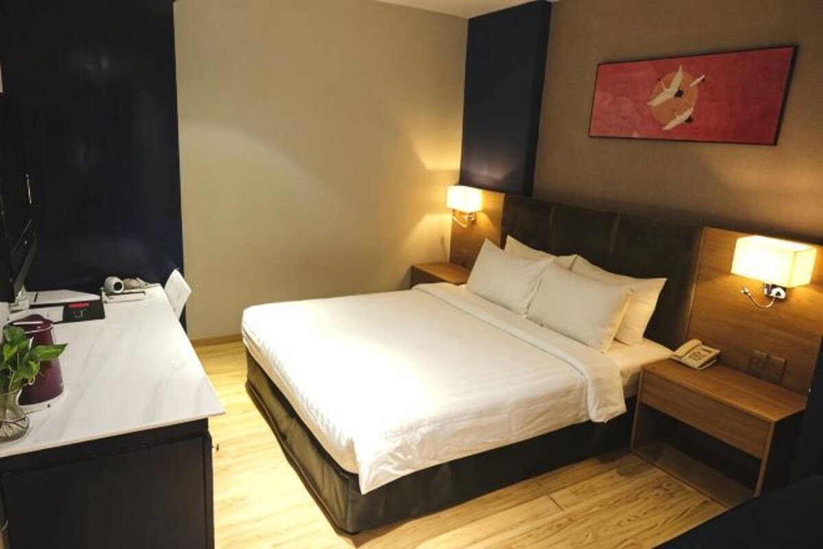 Een hotelkamer met een bed, nachtkastjes, een bureau en een stoel.