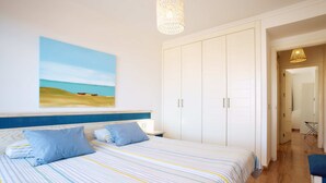 A bedroom with a bed, a painting, a wardrobe, and a bathroom visible through an open door. - Balcón del Mar (Puerto Rico)