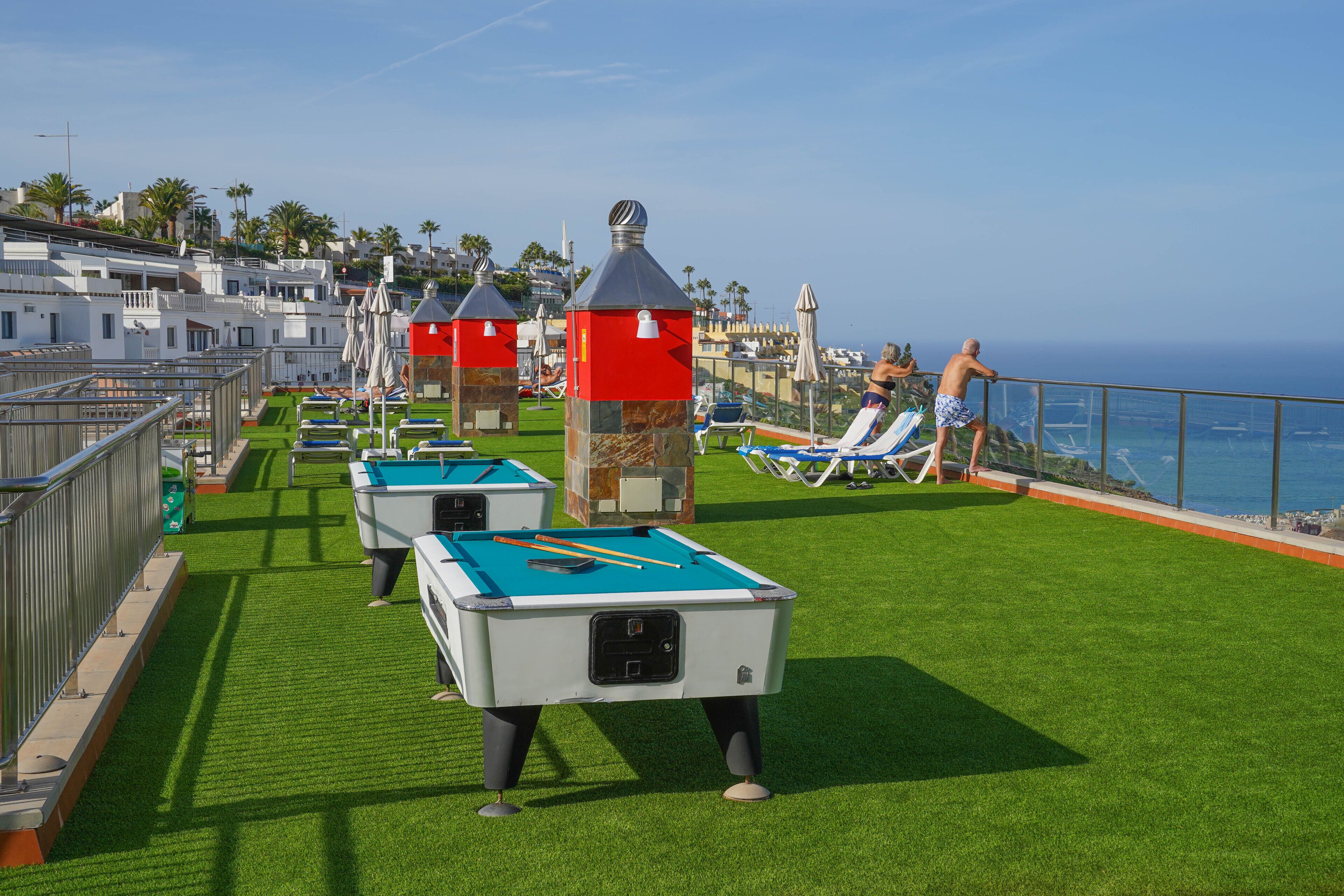 Zona de billar amb gespa artificial, taula de billar i seients relaxants al costat de la piscina.