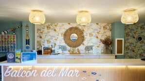 A reception desk with a sign reading "Balcón del Mar," surrounded by tropical wallpaper, a large mirror, and decorative items. - Balcón del Mar (Puerto Rico)