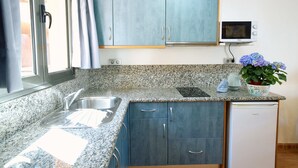 A kitchen with granite countertops, blue cabinets, a microwave, and a dishwasher. - Balcón del Mar (Puerto Rico)