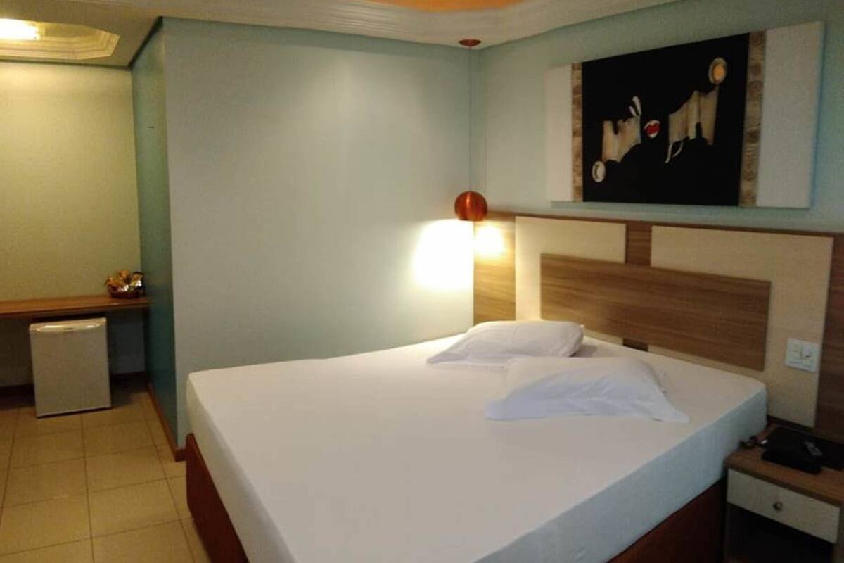 Ein Hotelzimmer mit Bett, Nachttisch, Schreibtisch und Lampe.