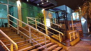 A staircase leading to a building with glass windows and a sign indicating a 24-hour service area. - Hotel Luni (São Paulo)