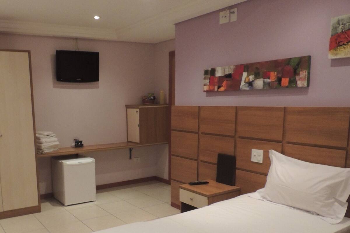 Ein Hotelzimmer mit einem Bett, einem Schreibtisch, einem Fernseher und einem kleinen Kühlschrank.