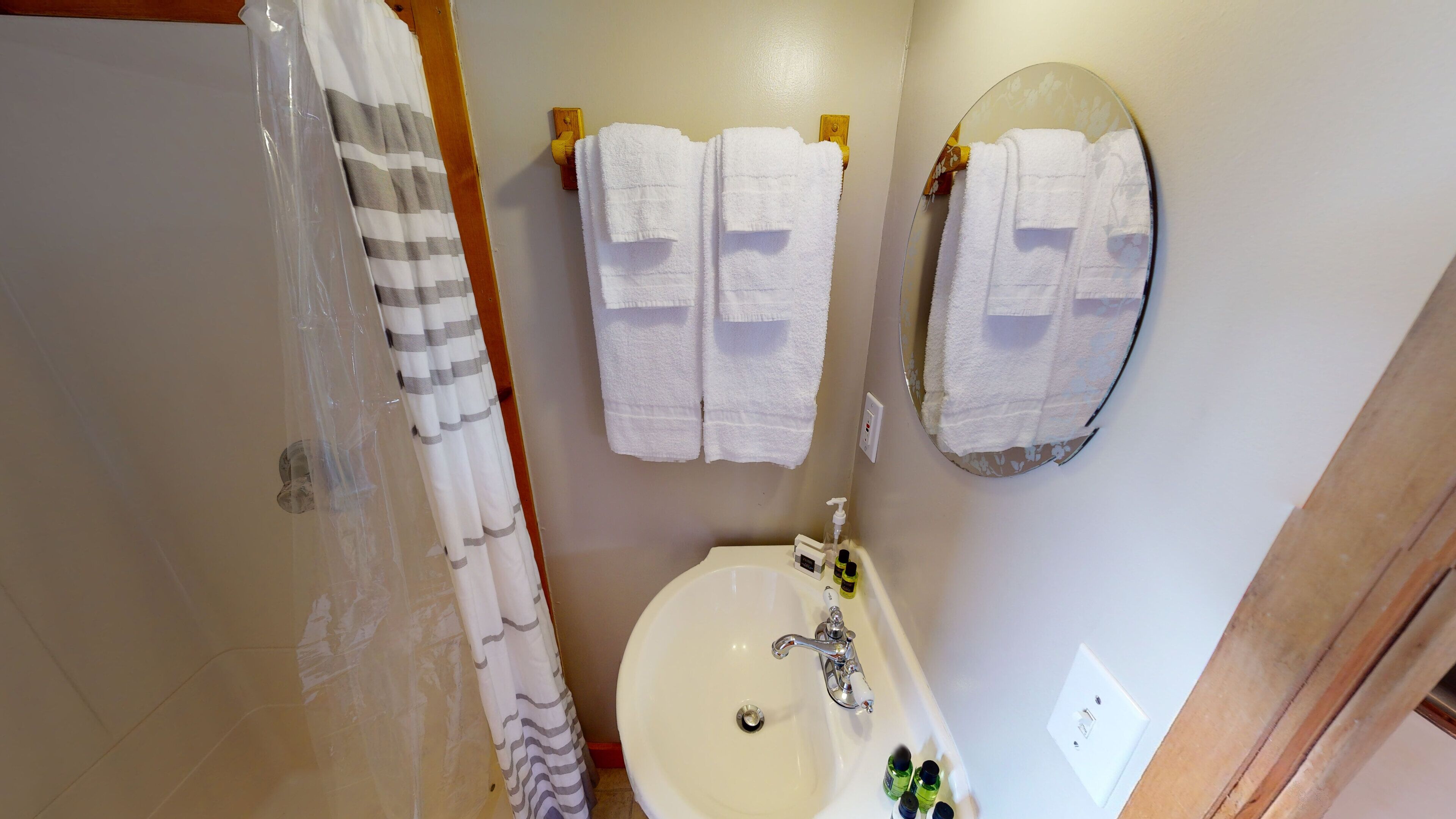 Une salle de bain avec une douche, un lavabo et deux serviettes suspendues à des crochets.