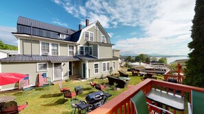 A two-story house with a large deck, outdoor seating, and a view of a lake. - Lakeview House & Cottages (Laconia)